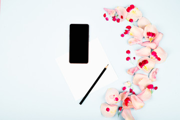 Female workspace with flowers and paper card. Top view feminine background.
