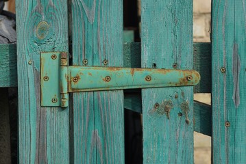 one green iron door hinge in rust on wooden boards door on the street