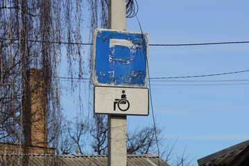 two road signs on a concrete pillar in the street against a blue sky