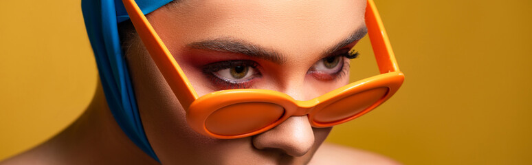 panoramic shot of fashionable girl in scarf and trendy sunglasses, isolated on yellow © LIGHTFIELD STUDIOS