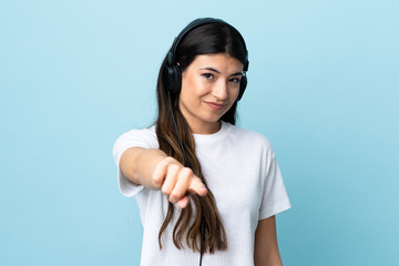 Young brunette girl over isolated blue background listening music