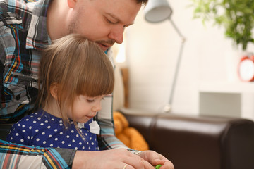 Dad play with cute little girl in blue dress on couch at home portrait
