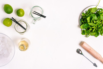 Mojito cooking process with copy space. Ingredients for a summer cocktail. Fresh mint, glass goblets, lime, rum and ice.