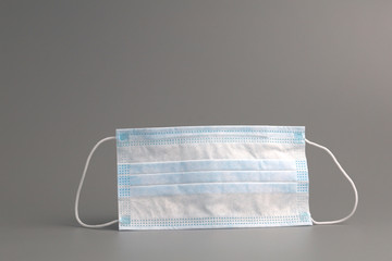 Surgical ear-loop mask on grey background.
