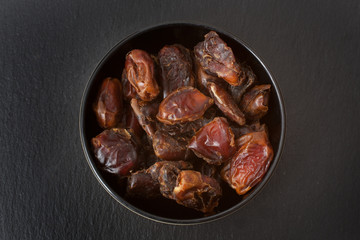 A studio photograph of a bowl of pitted dates