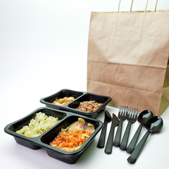 Plastic containers with delicious food and a paper bag on the table. Delivery service.