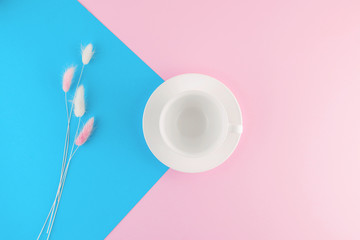 Empty coffee cup and flower on beautiful pink and bright blue pastel background.
