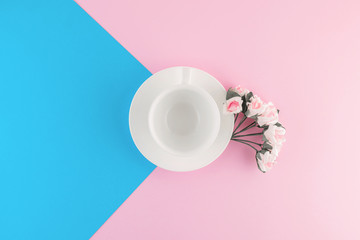 Empty coffee cup and flower on beautiful pink and bright blue pastel background.