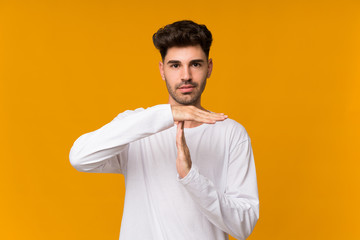 Young man over isolated orange background making time out gesture