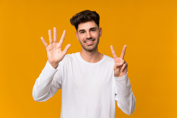 Young man over isolated orange background counting seven with fingers