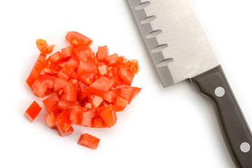 Heap of chopped tomato and a santoku knife on white