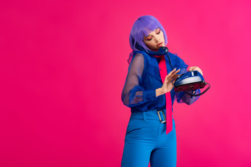 beautiful woman in purple wig talking on retro telephone, isolated on pink