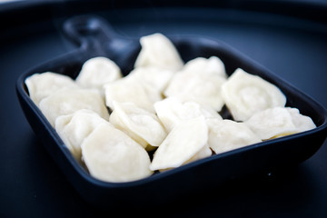 Raw fresh dumplings with meat or vegetarian dumplings with soy and spinach on black background. Food and cooking in the kitchen concept. Place for text. Copy space