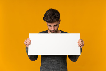 Young man over isolated background holding an empty white placard for insert a concept
