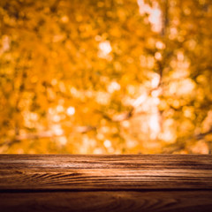 Naklejka na ściany i meble Empty wooden deck table with foliage bokeh background. Ready for product display montage.