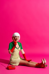 beautiful happy pop art girl in white wig talking on vintage telephone, on pink