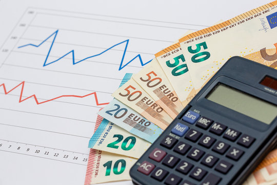 Business crisis and economic crisis concept image. Pile of Euro banknotes with calculator on analysis and data sheets.