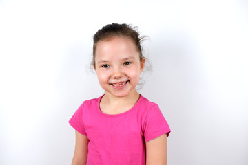 Cheerful cute caucasian little preschooler girl in a pink T-shirt smiles with a fallen milk tooth looking at the camera. Childhood, happiness, joy, child dentistry, goods and services for children