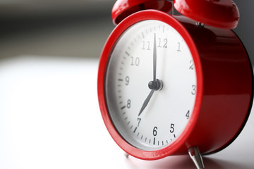 Red alarm clock set at seven in the morning closeup