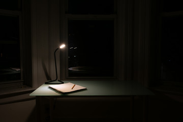 Home Desk at Night with a Light and Notebook with a Pencil