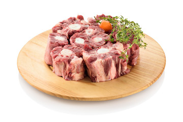 Raw oxtail, the culinary name for the tail of cattle, ready to be cooked. On a cutting board, isolated on white background.