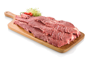 Raw flank steak, a cut of beef taken from the abdominal muscles or lower chest of the steer, ready to be cooked. On a cutting board with peppers aside, isolated on white background