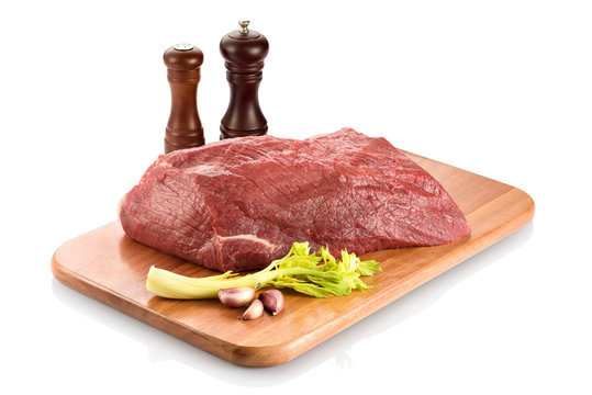 Raw silverside beef or outside flat, ready to be cooked. On a cutting board with some garlic aside, isolated on white background