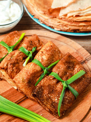 Tasty stuffed russian thin crepes with tuna, pottoes, cheese, eggs and green onion decoration. Vertical Orientation. Top view