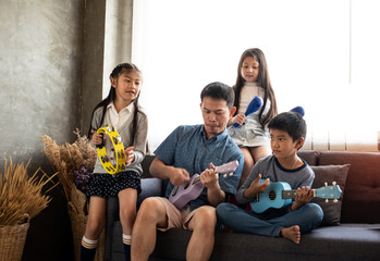 Father play music with daughter and son,at living room,relax time,family activity.