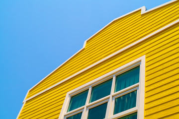 The yellow wooden house with mirror window and blue sky background