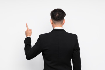 Young businessman over isolated white background pointing back with the index finger