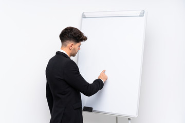 Young businessman giving a presentation on white board giving a presentation on white board and writing in it