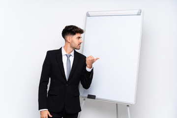 Young businessman giving a presentation on white board pointing to the side to present a product
