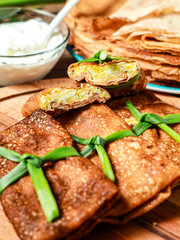 Two Parts Of Sliced Tasty stuffed russian thin crepes with tuna, potatoes, cheese, eggs and green onion decoration. Vertical Orientation.