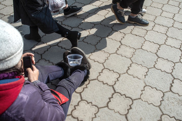 A beggar woman collects coins in the market.