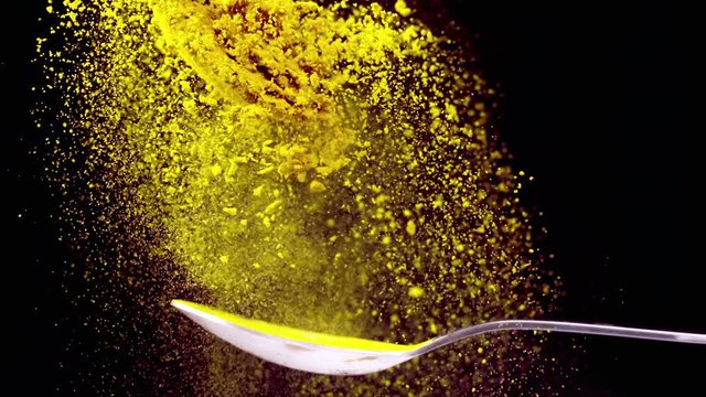 A Full Spoon Of exotic spice turmeric Flying up and Falling down on black background closeup in super slow Moti