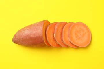 Sweet potato and slices on yellow background, top view