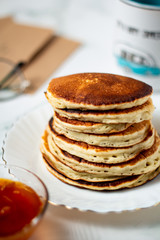Tasty breakfast with hot american pancakes with apricot jam on the white table. Mug and envelope background