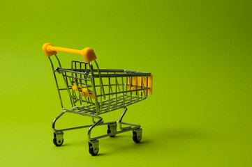 Trolley for shopping on a green background. Supermarket food price concept, holiday discounts