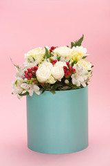 bouquet of flowers in turquoise gift box on pink background
