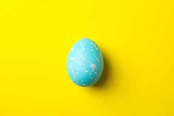 Blue Easter egg on yellow background, close up