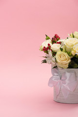 bouquet of flowers in festive gift box with bow on pink background