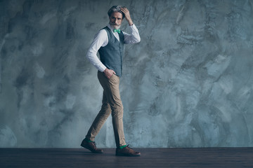 Obraz na płótnie Canvas Full length photo of senior macho business man check neat hairstyle walk corporate meeting wear specs shirt waistcoat pants green tie shoes isolated concrete grey color wall background
