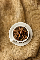 A scattering of coffee beans with a cup of coffee.