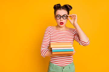 Photo of pretty lady student open mouth have to study late night hold many books wear freak nerd specs striped red white shirt green pants isolated bright yellow color background