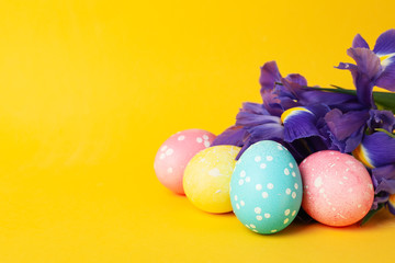 Easter eggs and Iris flowers on yellow background, space for text