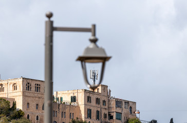 Fototapeta na wymiar View of a group of antennas standing on the roof of a building through a street lamp in old district of Jerusalem city in Israel