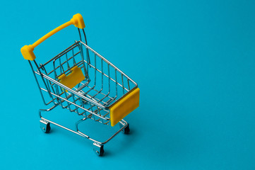 Trolley for shopping on a blue background. Supermarket food price concept, holiday discounts