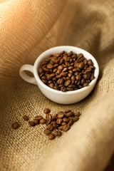 A scattering of coffee beans with a cup of coffee.