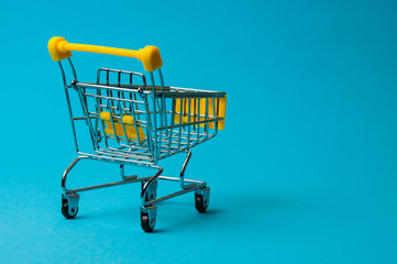 Trolley for shopping on a blue background. Supermarket food price concept, holiday discounts